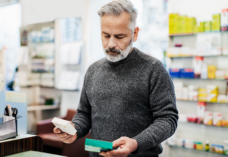Man looking down at two boxes of medicine