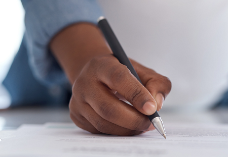 Hand holding a pen writing on a piece of paper