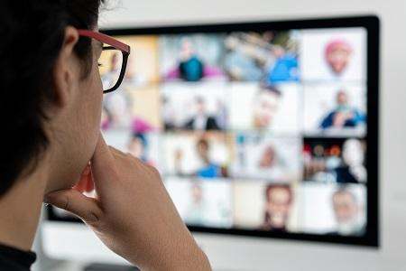 View over a person's shoulder as they look at a computer screen with a Zoom meeting in progress