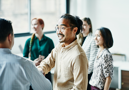 An Asian man talking to another man in a group in a room