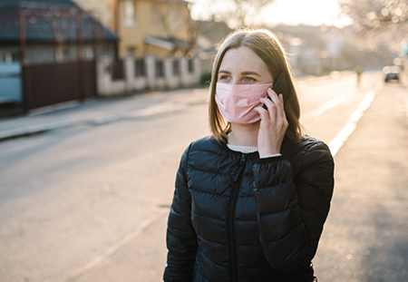 A young woman talking on the phone in a small town with a dirt road