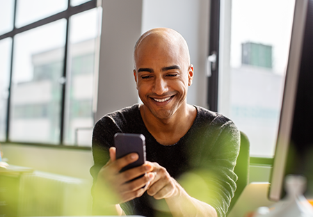  A bold man smiling and looking at his phone