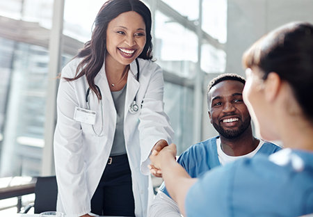 A young minority medical woman greeting another medical woman with a handshake
