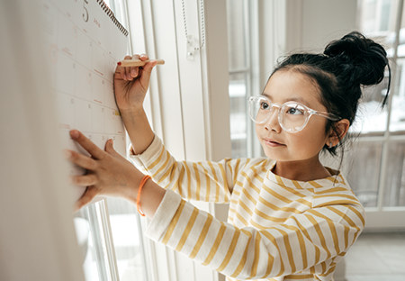 A young female child writing on a whiteboard
