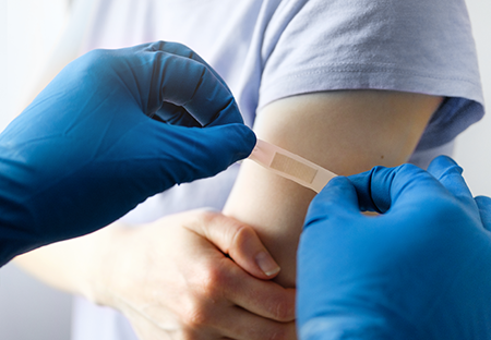 Someone receiving a band aide after a vaccine in their arm