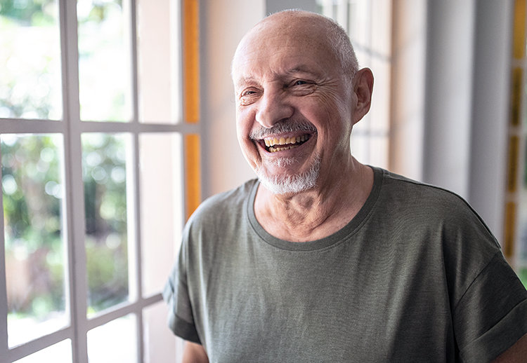 Elderly man smiling in a room with a window