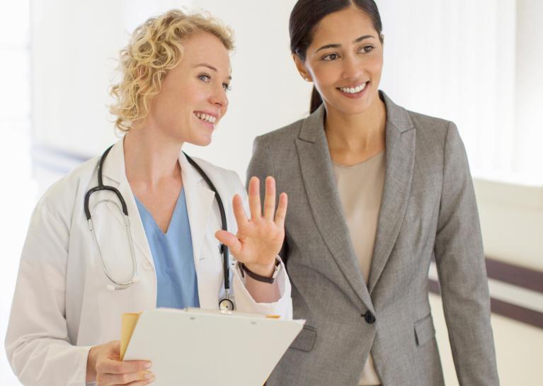 Surveyor walks down hospitall hallway with doctor